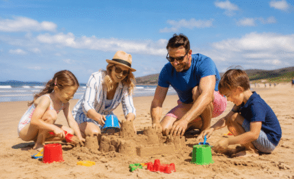 Family building sandcastles on sunny beach near hotel, enjoying playtime, blue sky, ocean view, and family-friendly fun.