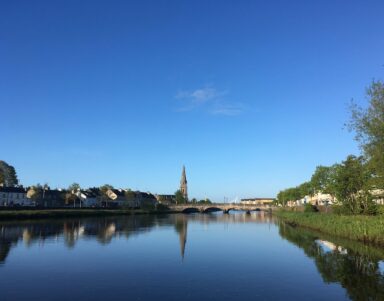 Stunning river view with historic bridge and church, nearby hotel offers serene escape and picturesque surroundings.