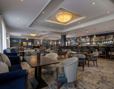 Elegant hotel lounge with plush seating, ambient lighting, and a well-stocked bar. Ideal for relaxation and socialising.
