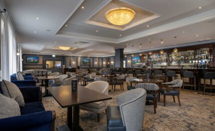 Elegant hotel bar with plush seating, exquisite chandelier, and well-stocked bar, offering a welcoming atmosphere.