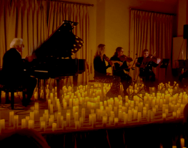 Experience a candlelit live music performance with a grand piano and string quartet in an elegant hotel event space.