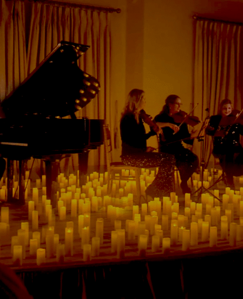 Experience a candlelit live music performance with a grand piano and string quartet in an elegant hotel event space.
