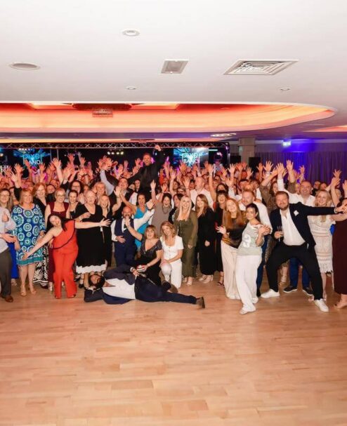 Guests enjoying a lively party in a spacious hotel ballroom with elegant lighting and vibrant atmosphere.