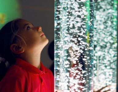 Child mesmerised by bubble column feature in vibrant hotel lobby, highlighting family-friendly amenities and modern design.