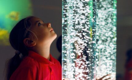 Child mesmerised by bubble column feature in vibrant hotel lobby, highlighting family-friendly amenities and modern design.