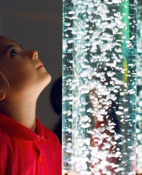 Child mesmerised by bubble column feature in vibrant hotel lobby, highlighting family-friendly amenities and modern design.