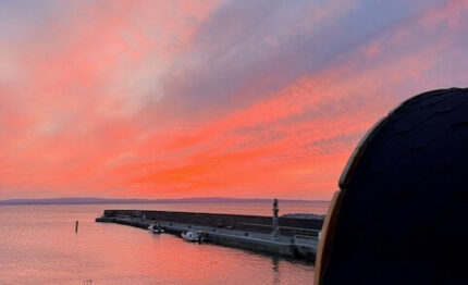 Stunning sunset view over the serene harbour, with a cosy outdoor sauna, perfect for relaxation near the sea.