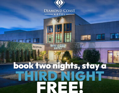 Elegant Diamond Coast Hotel facade at dusk, glowing entrance, lush greenery; inviting offer for extended stay.