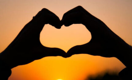 Guests enjoy a romantic sunset view, with silhouettes of hands forming a heart against an orange sky. Perfect for couples' getaway.