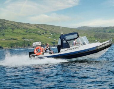 Guests enjoy a thrilling speedboat ride on scenic coastal waters with lush hills in the background at a premier seaside hotel.