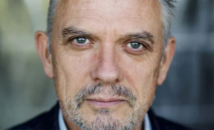 Close-up of mature guest's grey-streaked hair, blue eyes and trimmed moustache conveying relaxed, welcoming boutique hotel atmosphere